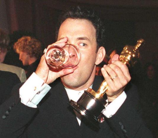 US actor Tom Hanks holds up his Oscar as he drinks